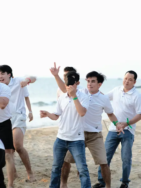 A group of friends laughing and jumping together on the shoreline