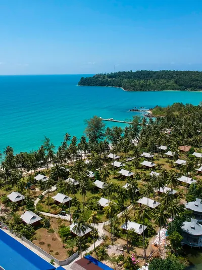 Resort grounds and a swimming pool seen from the air beside moored boats