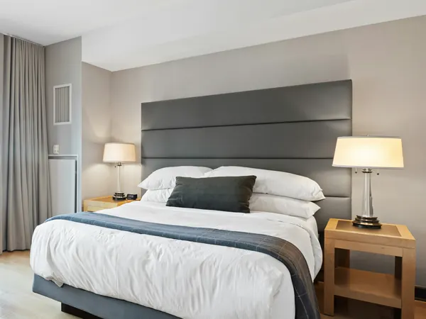 A larger room with a double bed, side table and seating area