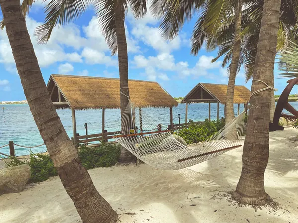 Nipa-roofed cabanas and hammocks strung between palms above the sand